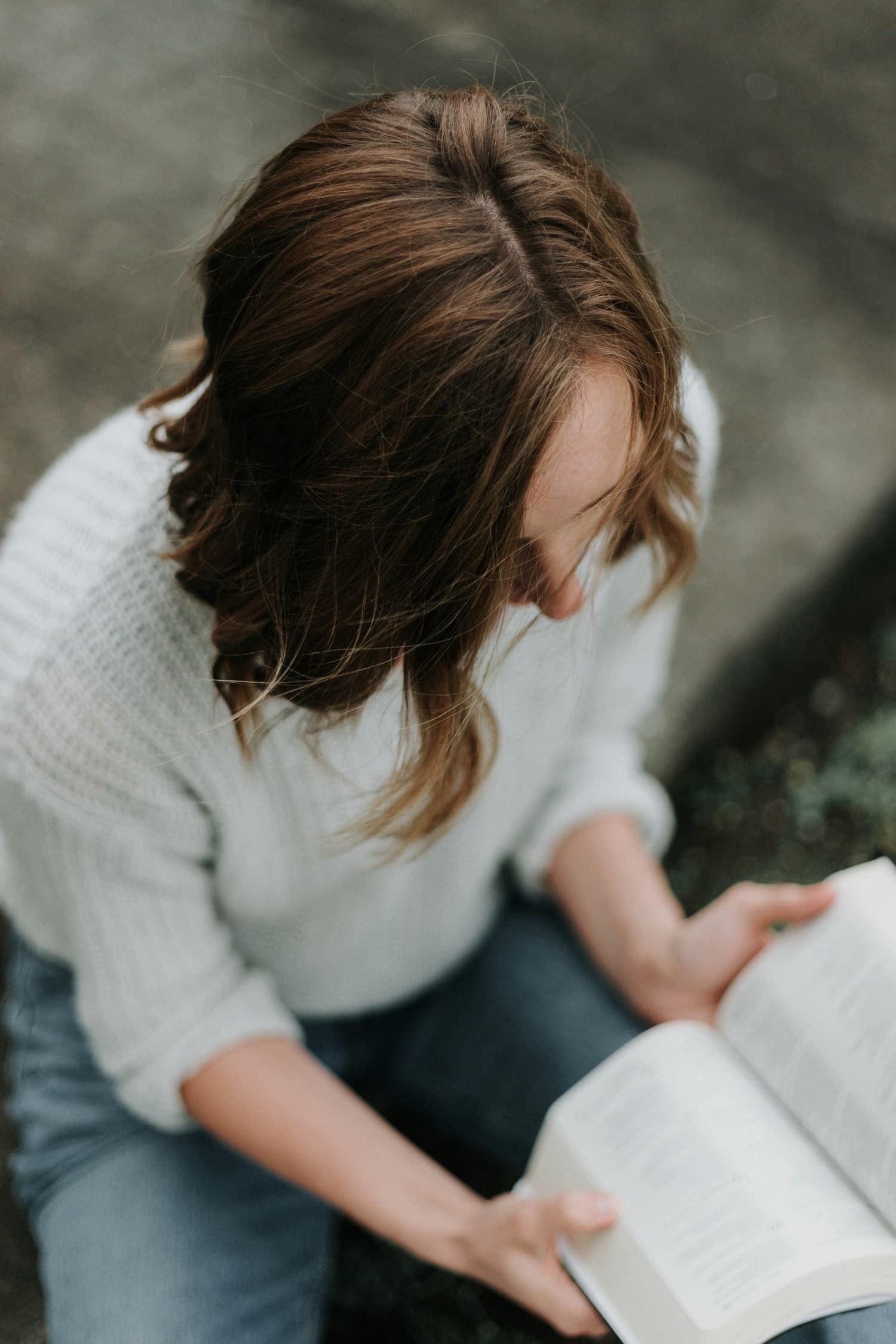 Una mujer leyendo un libro abierto, vista desde arriba.