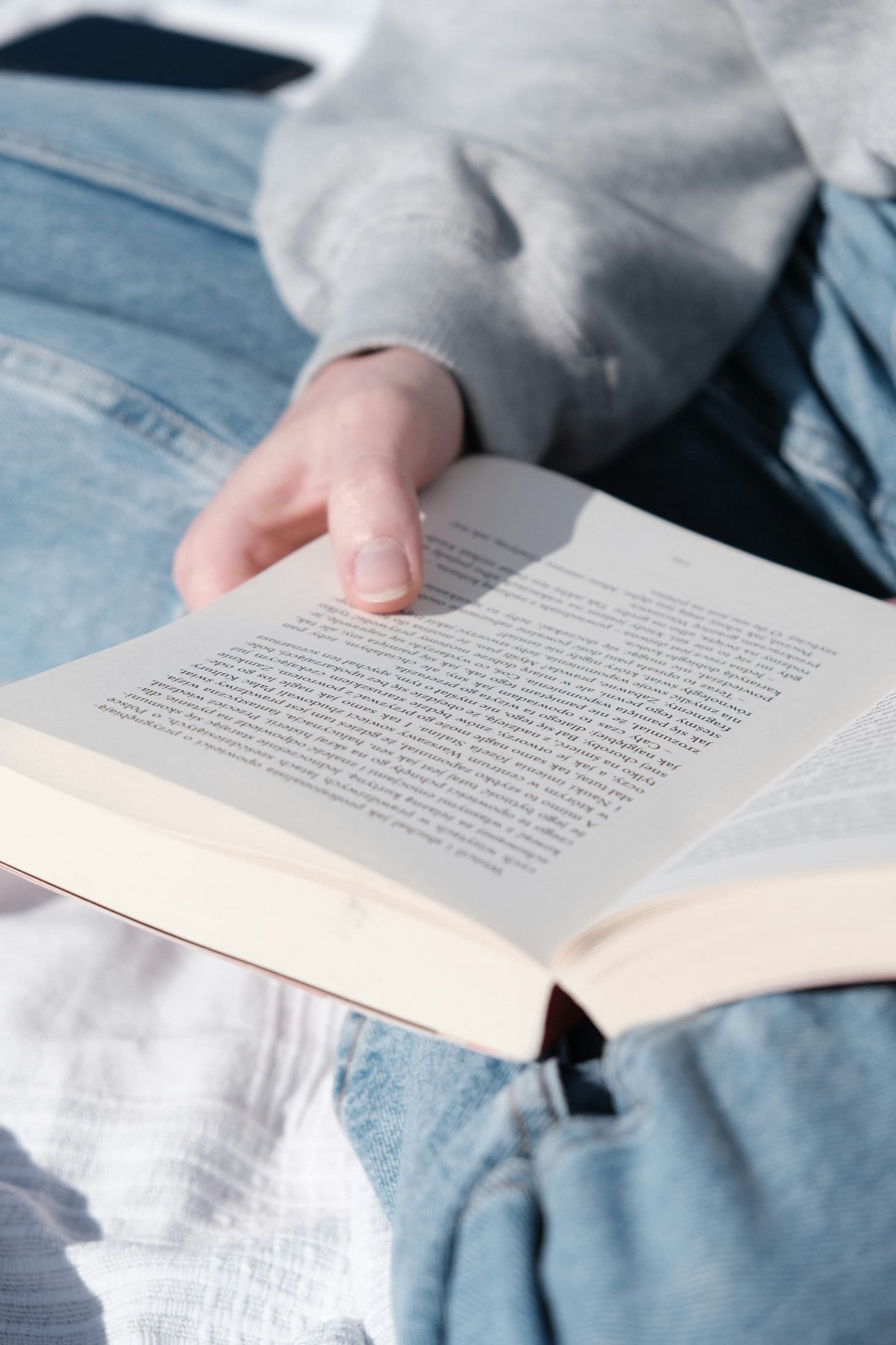 Una mano sostiene un libro abierto, leído al sol.